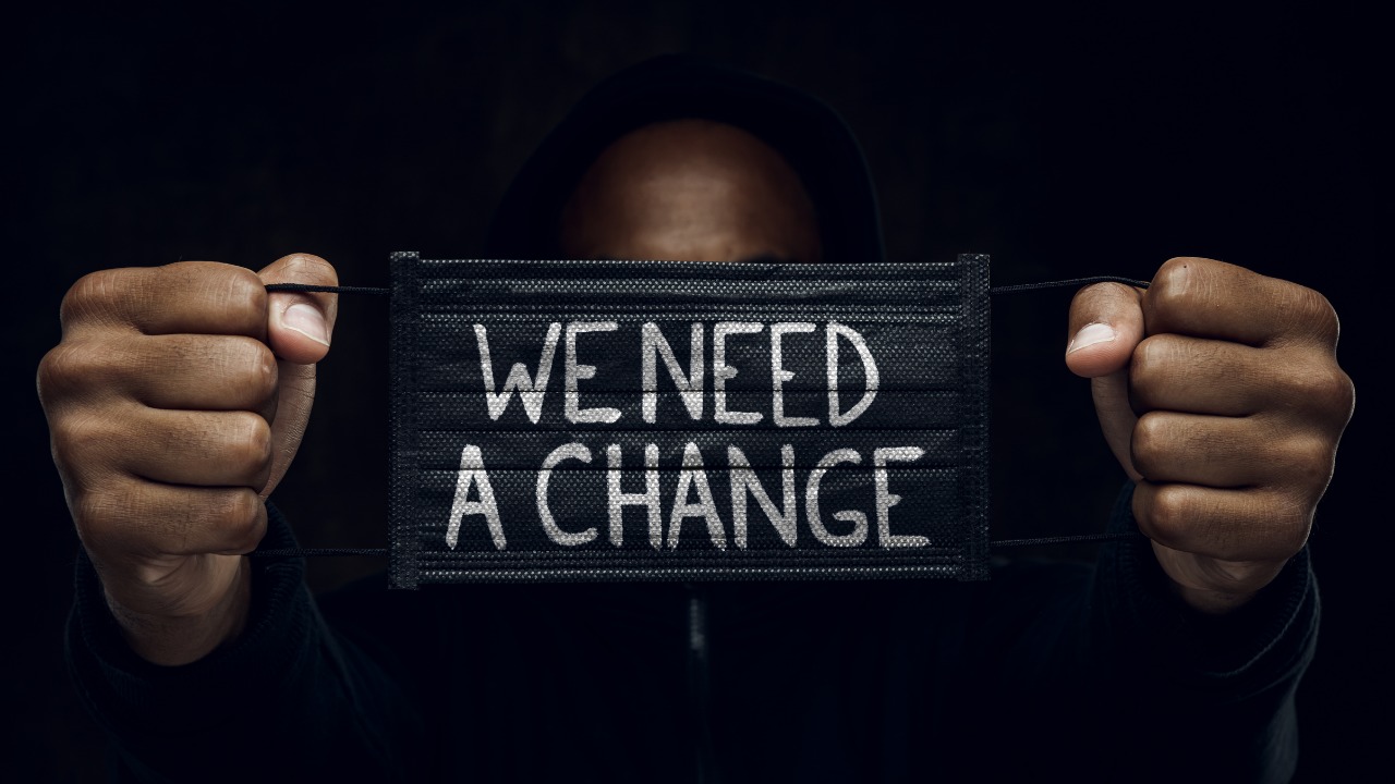 We need a change, black man holding sign with words