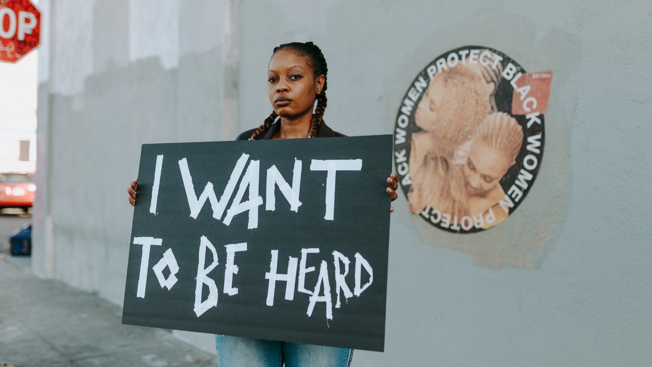 Black woman holding a sign that says, I want to be heard