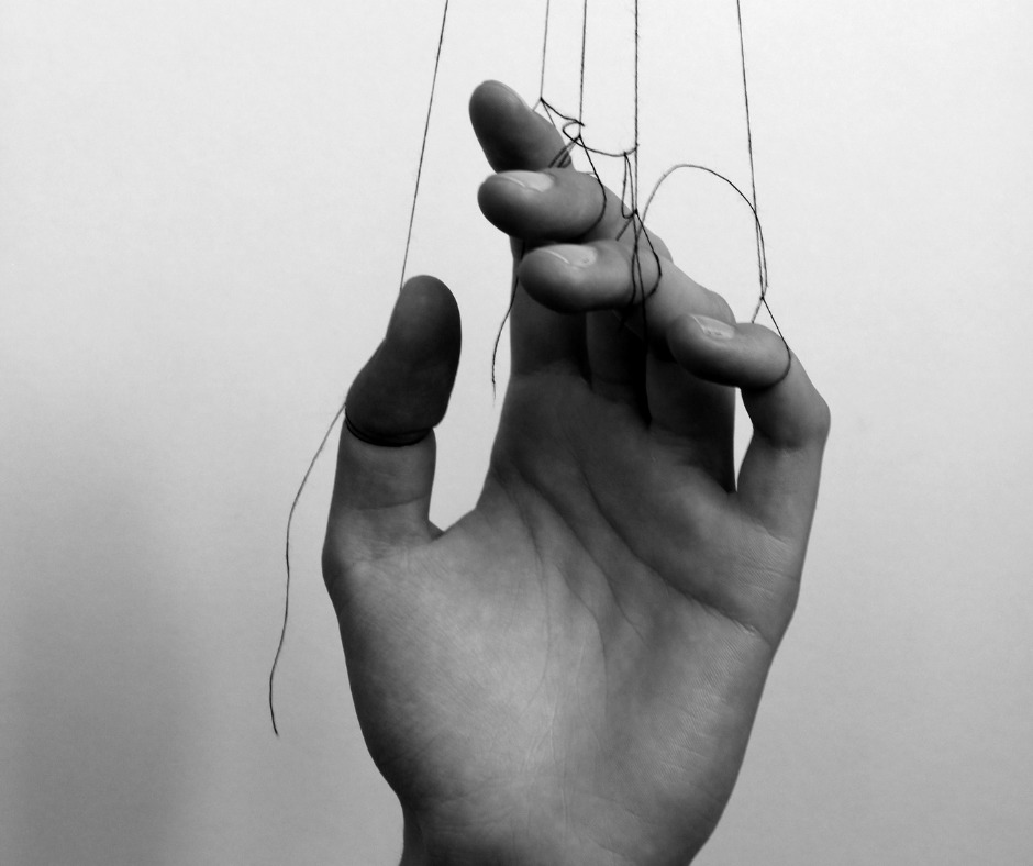 hand with strings attached to illustrate manipulation and gaslighting - mindful soul center magazine