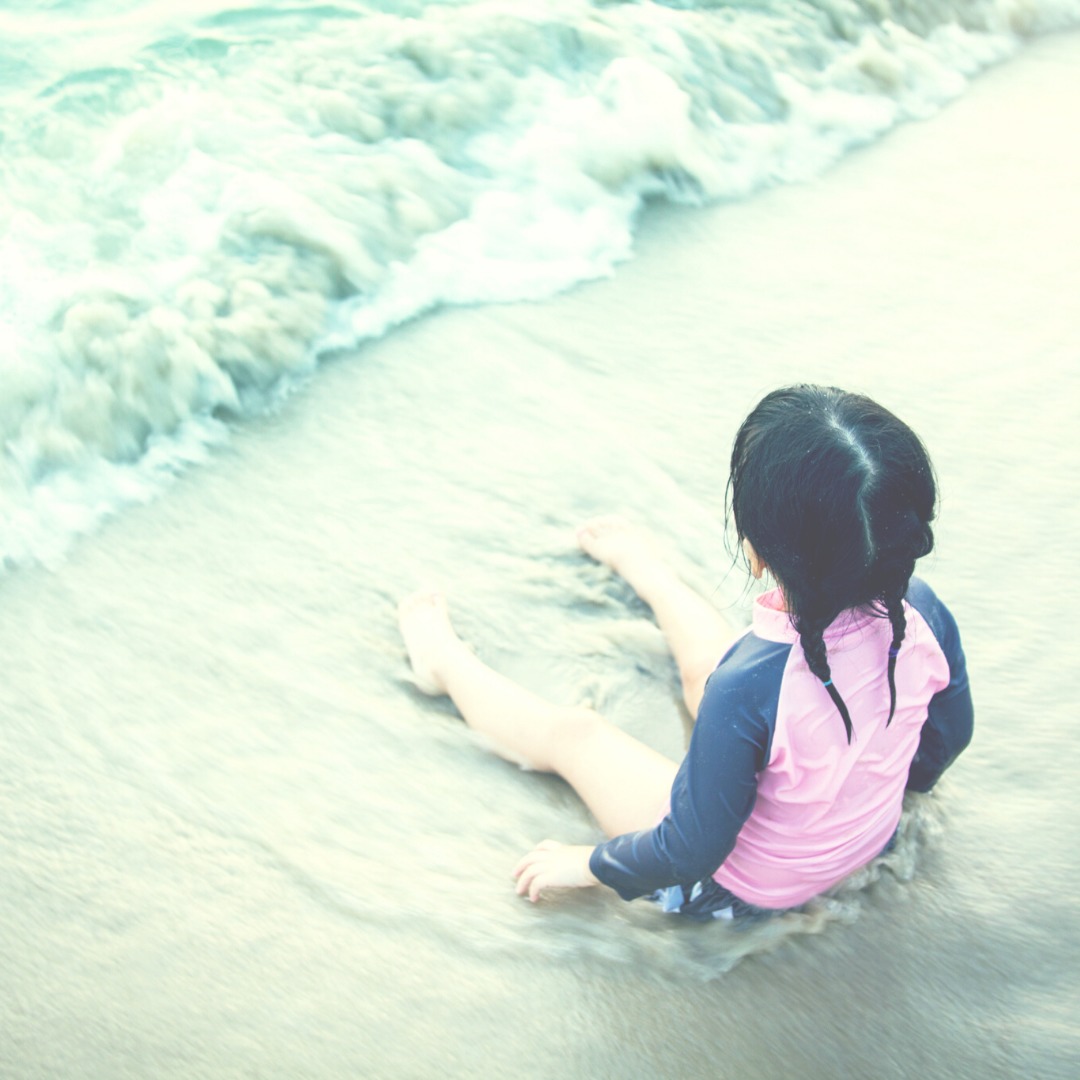 Retro Picture of young girl in pink shirt sitting at water's edge